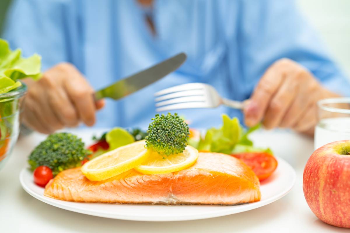 Asian elderly woman patient eating salmon steak breakfast with vegetable healthy food in hospital.