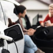 conversation-near-charging-electric-vehicle-outsid-2024-07-03-20-16-18-utc (1)