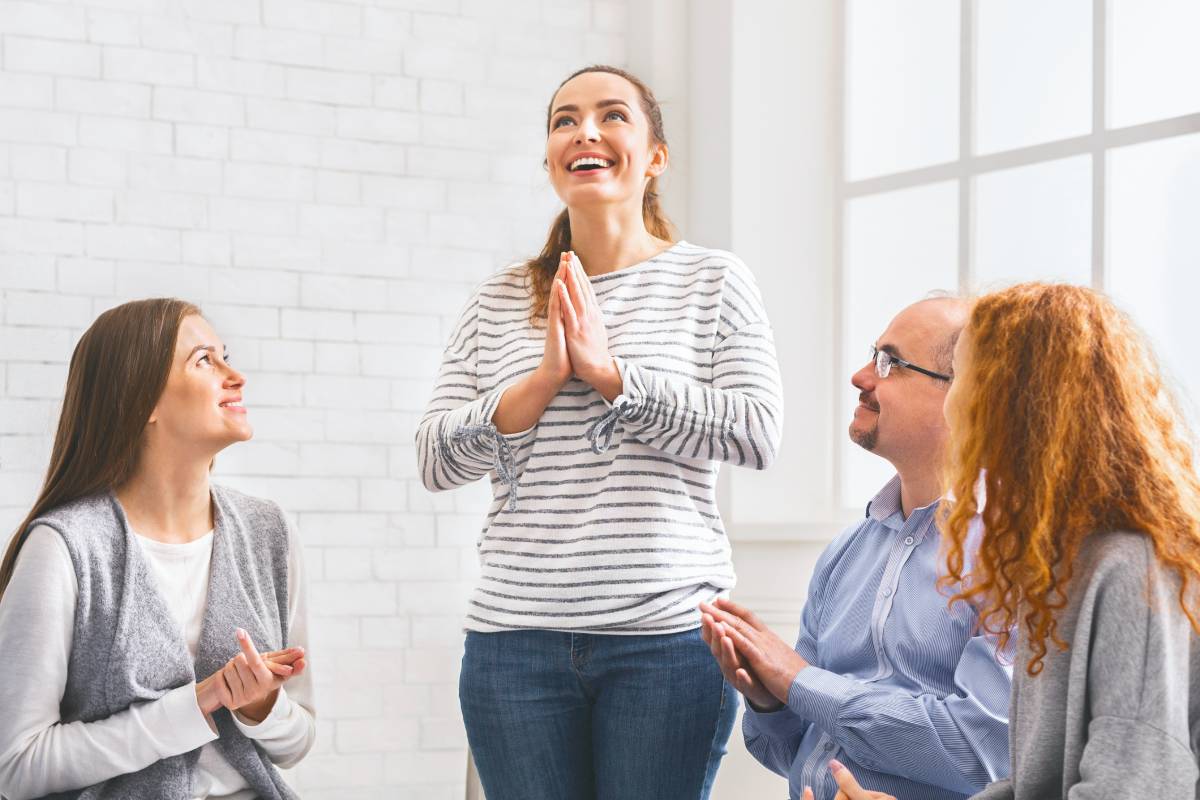 Community members clapping to woman, supporting her at therapy group meeting