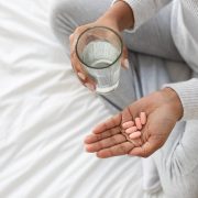 Person Preparing to Take Medication With Glass of Water