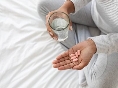 Person Preparing to Take Medication With Glass of Water