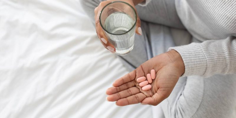 Person Preparing to Take Medication With Glass of Water