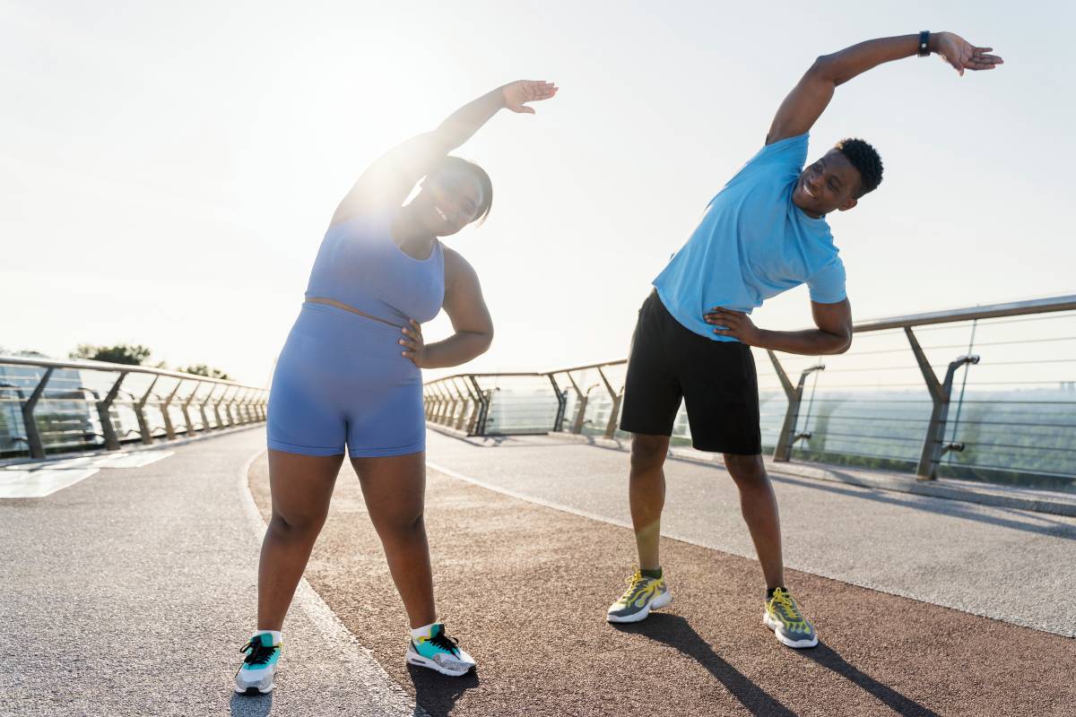 Positive african american man and woman working out on street, doing exercises in park