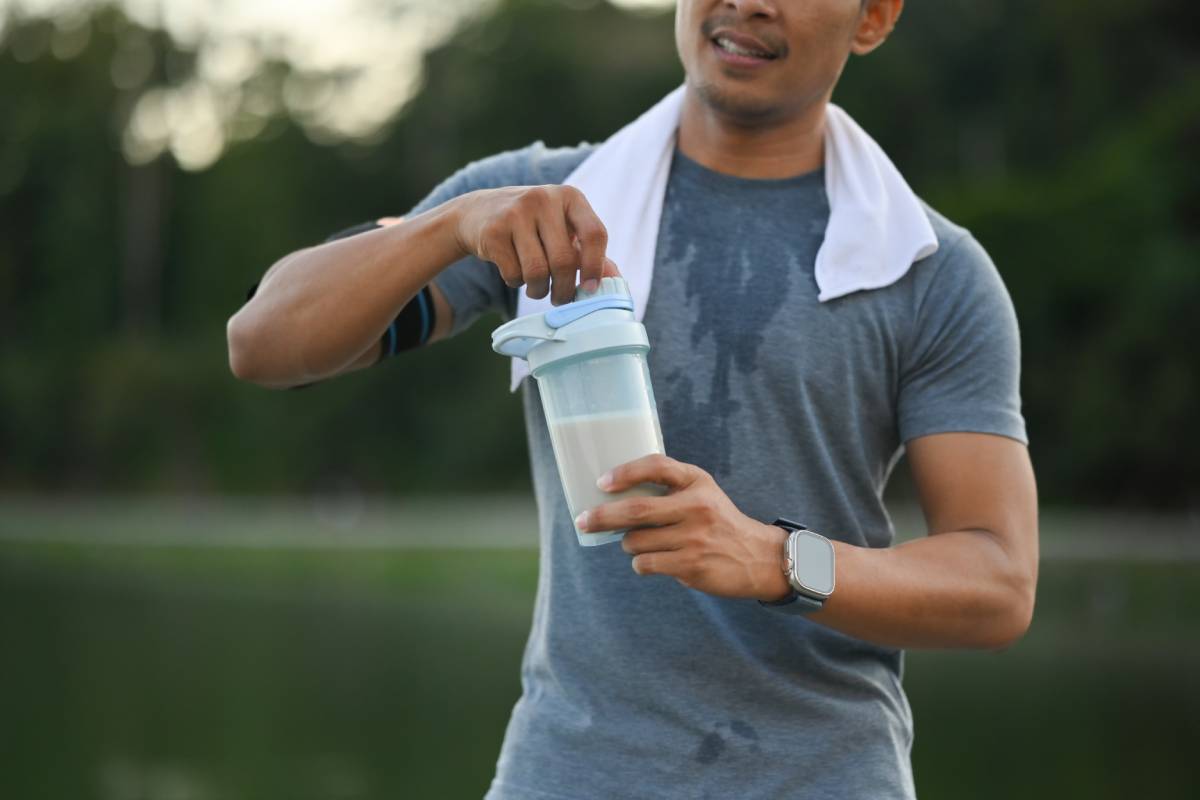 Image of athletic sportsman drinking protein shake after morning cardio workout in the park