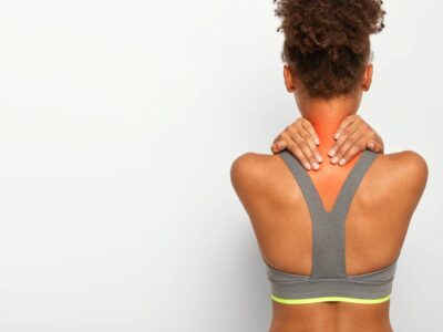 Cropped image of faceless African American woman touches neck with both hands, shows problematic zone, being injured, dressed in active wear, poses over white studio wall, blank space for text