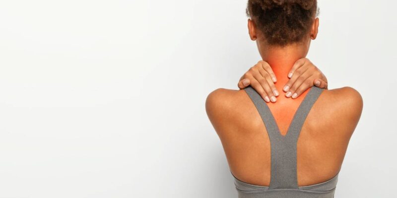 Cropped image of faceless African American woman touches neck with both hands, shows problematic zone, being injured, dressed in active wear, poses over white studio wall, blank space for text