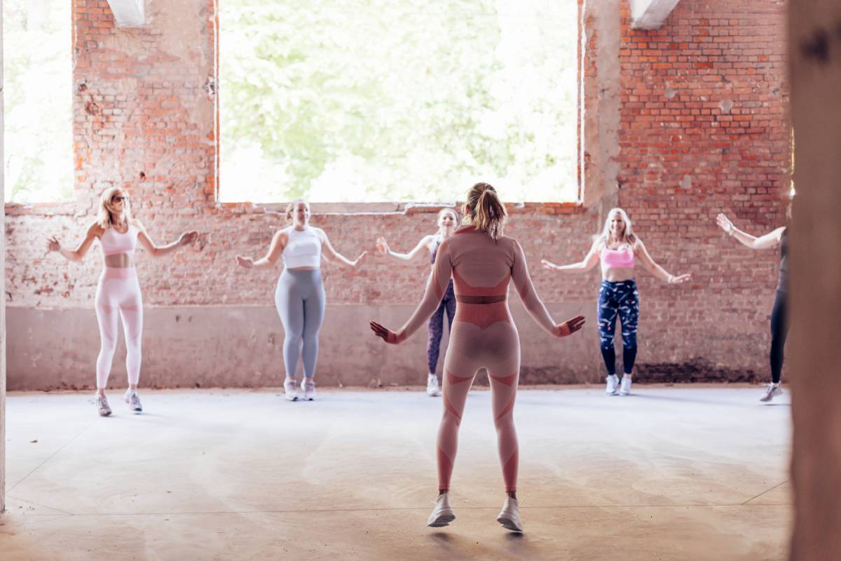 Fitness instructor leading jumping jack exercise in industrial gym