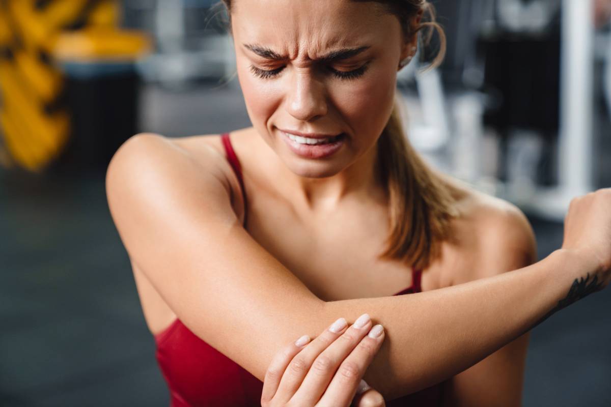 Unhappy athletic sportswoman with elbow pain working out in gym