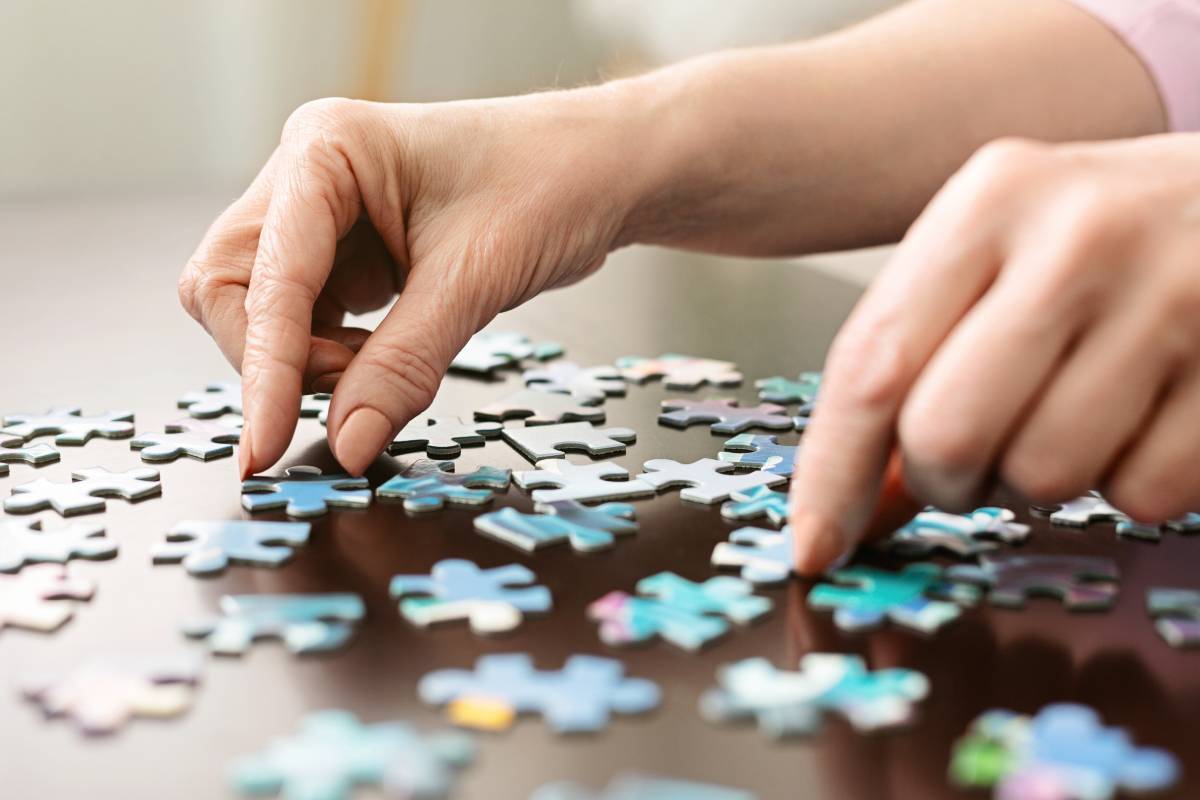 Elderly woman hands doing jigsaw puzzle closeup