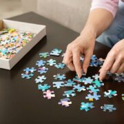 Elderly woman hands doing jigsaw puzzle closeup