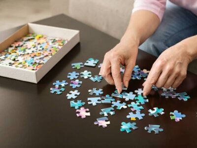 Elderly woman hands doing jigsaw puzzle closeup